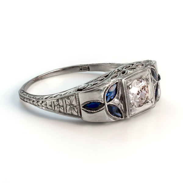 Angled interior view of an 18k white gold Art Deco shield ring showing the gold hallmark and intricate foliate sapphire shoulders.