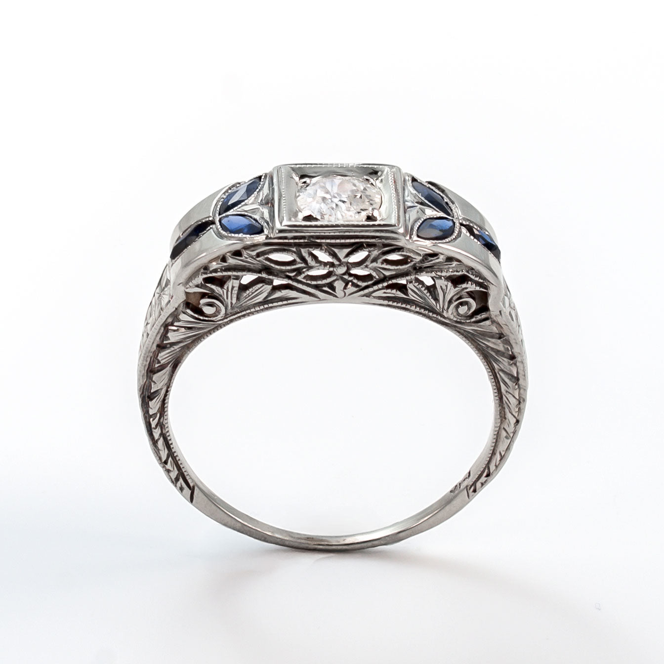 Top view of an 18k white gold Art Deco shield ring with a 5mm central diamond and marquise sapphire accents.