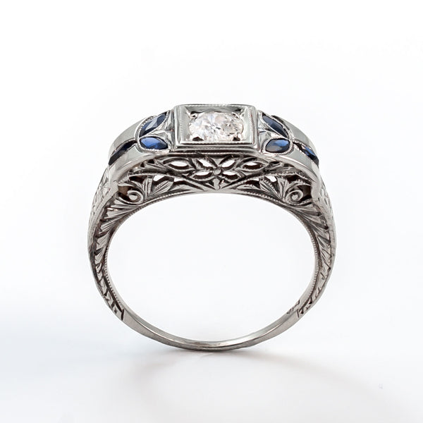 Top view of an 18k white gold Art Deco shield ring with a 5mm central diamond and marquise sapphire accents.