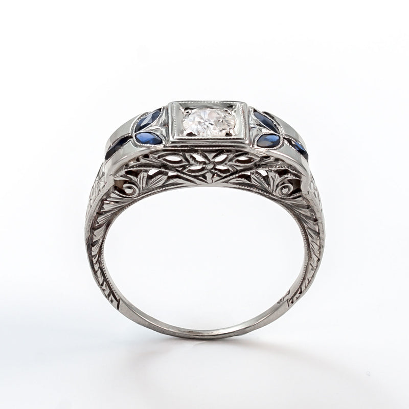 Top view of an 18k white gold Art Deco shield ring with a 5mm central diamond and marquise sapphire accents.