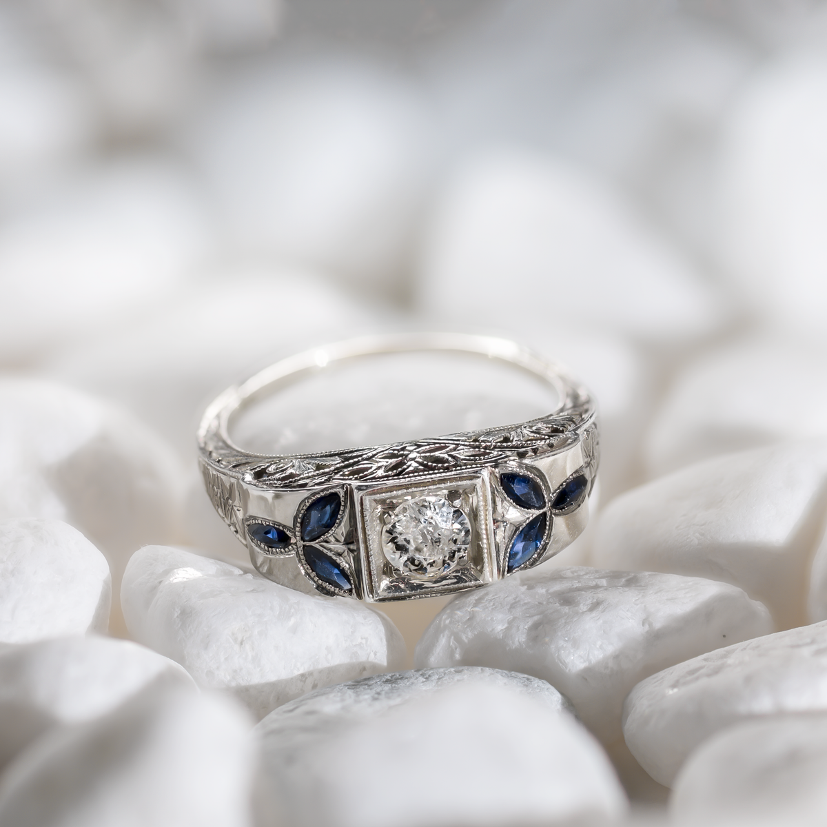 Lifestyle view of an Art Deco 18k white gold target ring featuring a 5mm central diamond and marquise sapphire accents on white stones.