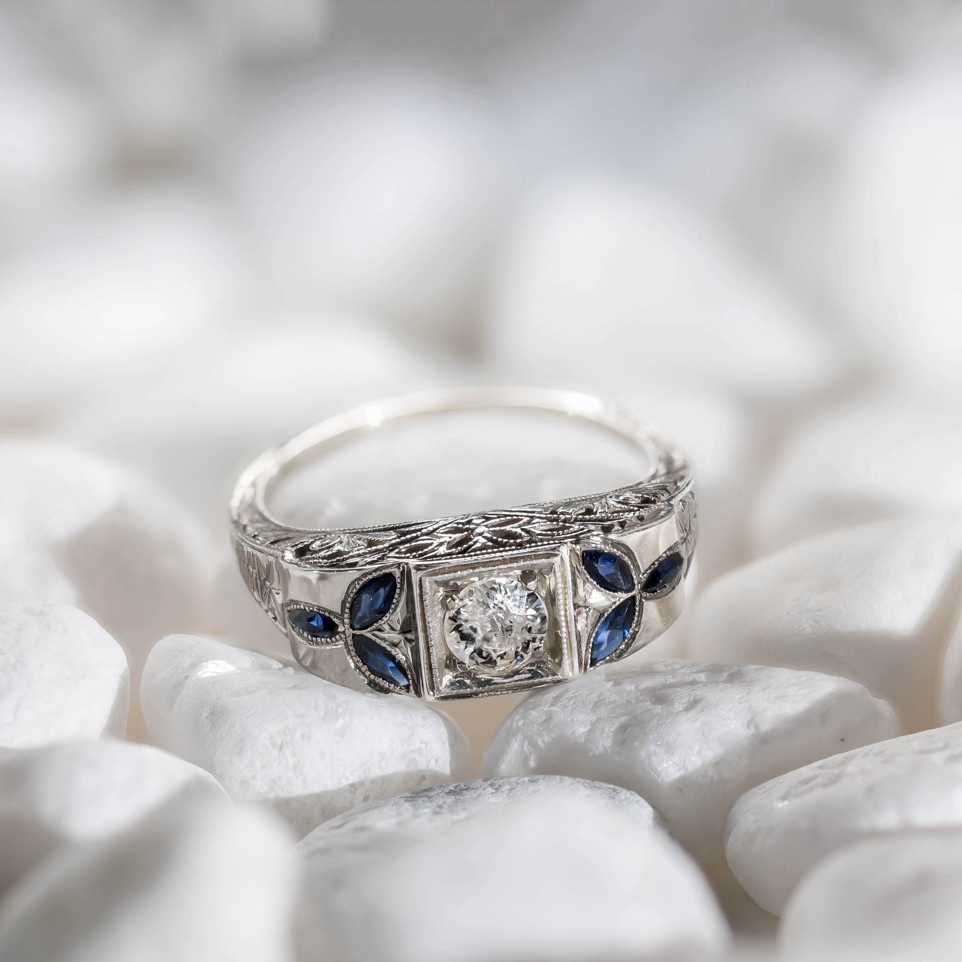 Lifestyle view of an Art Deco 18k white gold target ring featuring a 5mm central diamond and marquise sapphire accents on white stones.