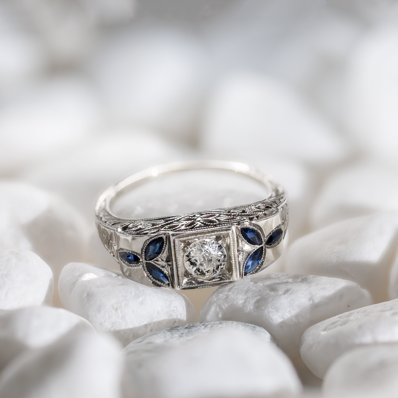 Lifestyle view of an Art Deco 18k white gold target ring featuring a 5mm central diamond and marquise sapphire accents on white stones.