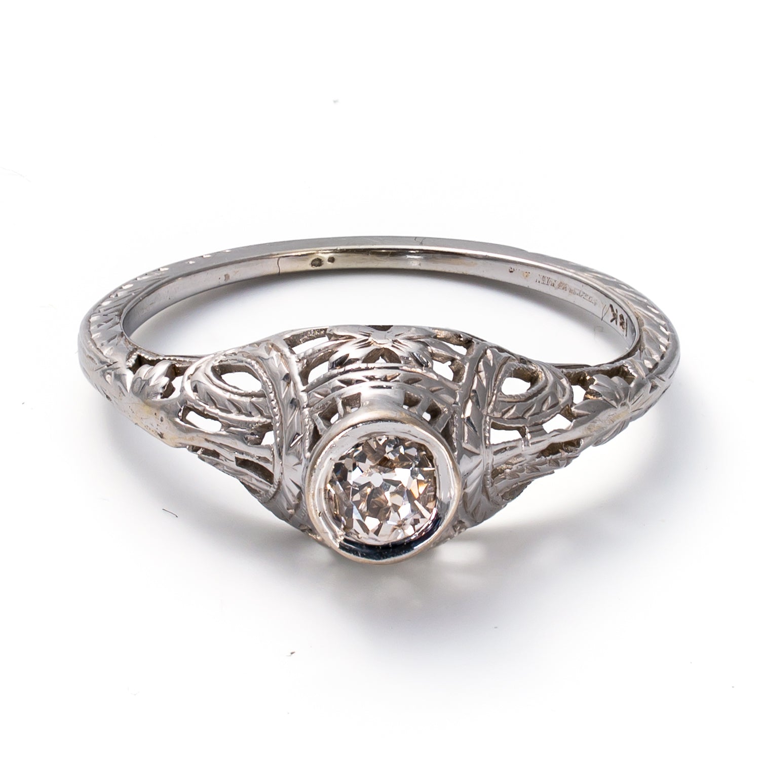 Front elevated view of an authentic Edwardian to early Art Deco transitional ring featuring a bezel-set antique hand-cut diamond in 18K gold.
