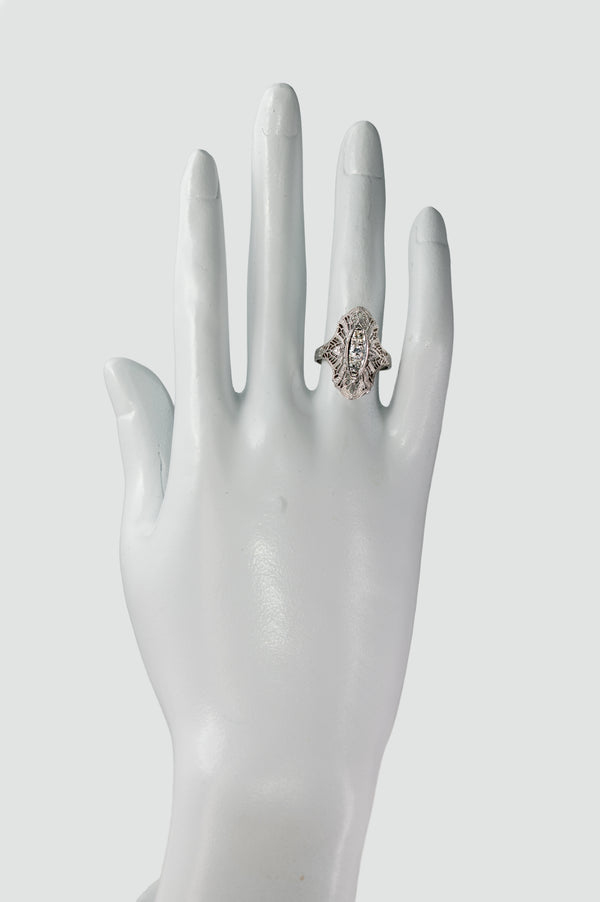 Art Deco diamond filigree navette ring worn on a display hand showing elongated finger coverage.