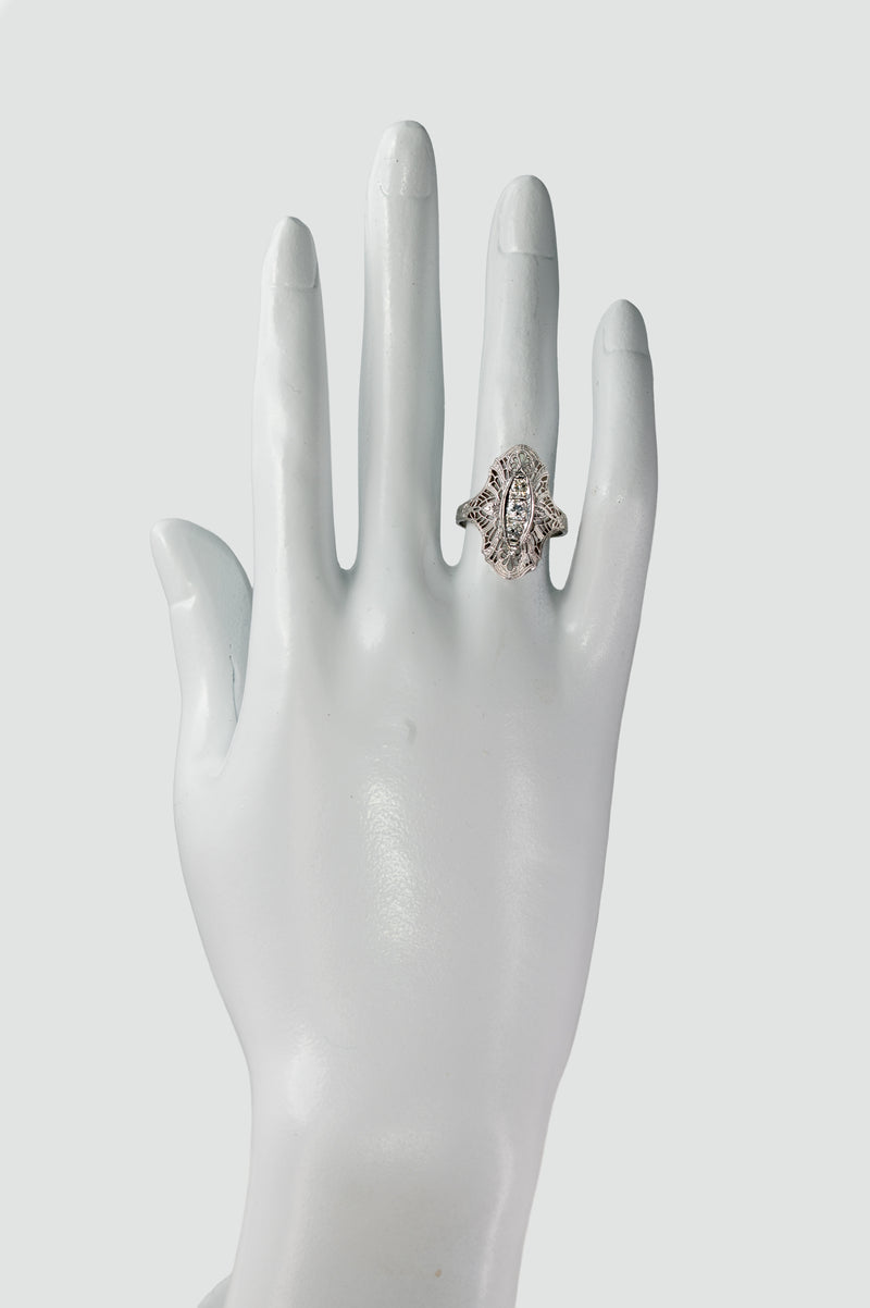 Art Deco diamond filigree navette ring worn on a display hand showing elongated finger coverage.
