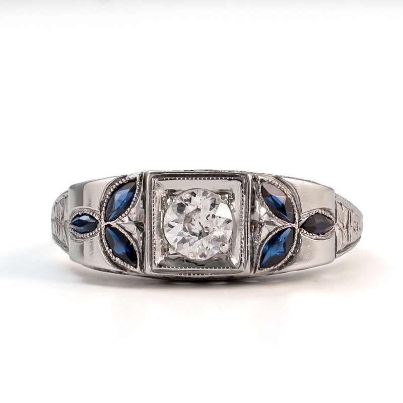Straight-on studio view of an 18k white gold shield ring featuring a 5mm Old European Cut diamond and marquise sapphire accents.