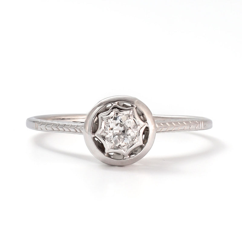 Front view of a 14k white gold diamond solitaire ring with an intricate star-shaped bezel and slim polished band.