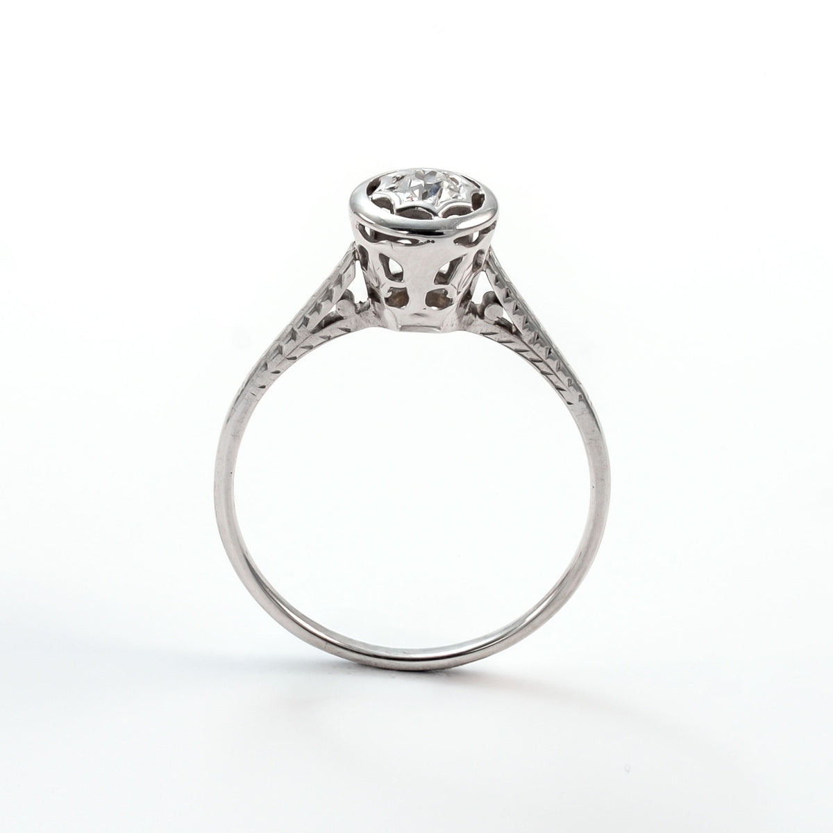 Frontal view of a 14k white gold diamond solitaire ring with an intricate star-shaped bezel and slim polished band.