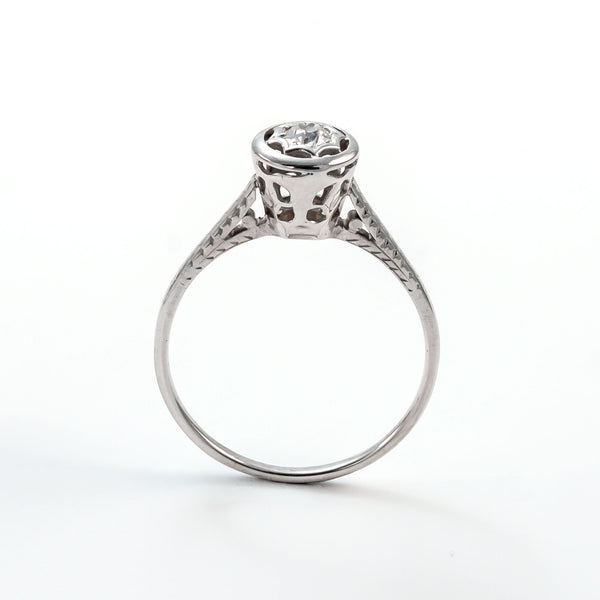 Frontal view of a 14k white gold diamond solitaire ring with an intricate star-shaped bezel and slim polished band.