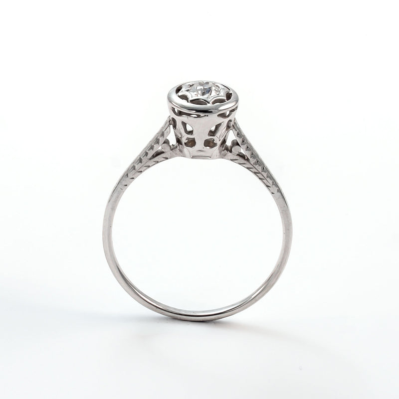 Frontal view of a 14k white gold diamond solitaire ring with an intricate star-shaped bezel and slim polished band.