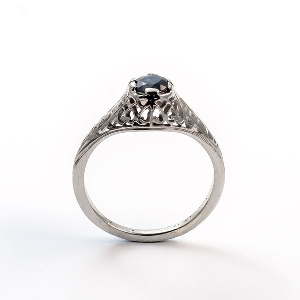 Elevated straight-on view of a vintage sapphire ring in a secure four-prong filigree mounting.