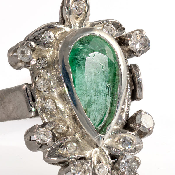 Macro detail of foliate diamond accents sculpted leaves and bezel setting on vintage 1940s palladium emerald ring