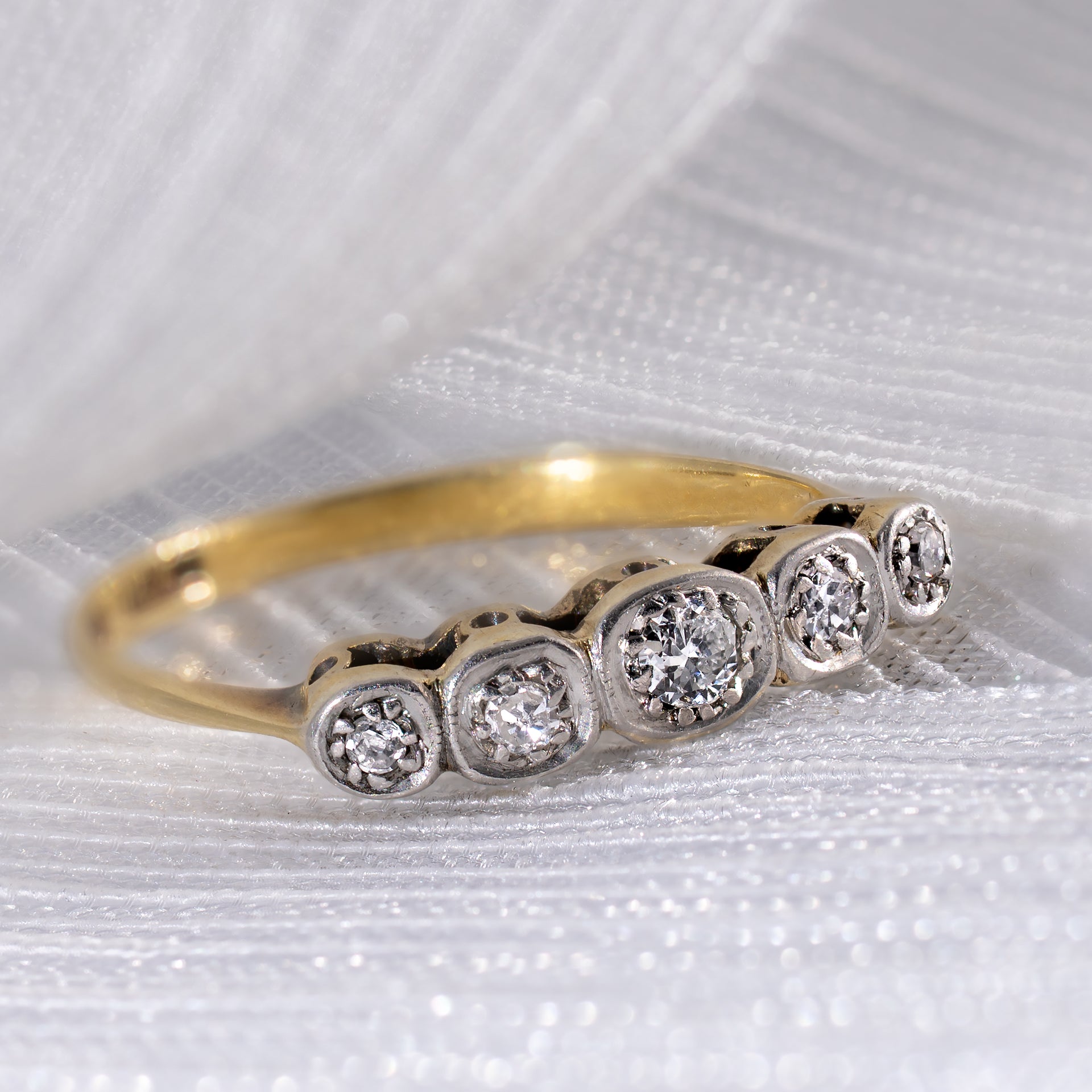 Antique Edwardian 0.15ctw Old European Cut diamond 5-stone ring on white silk background, showing platinum illusion settings and 18ct yellow gold band.
