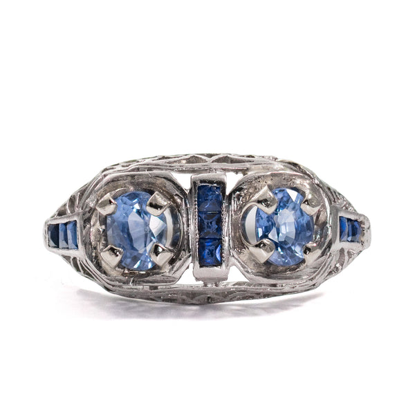 Front view of an antique Edwardian sapphire ring with natural untreated blue sapphires and intricate open filigree.