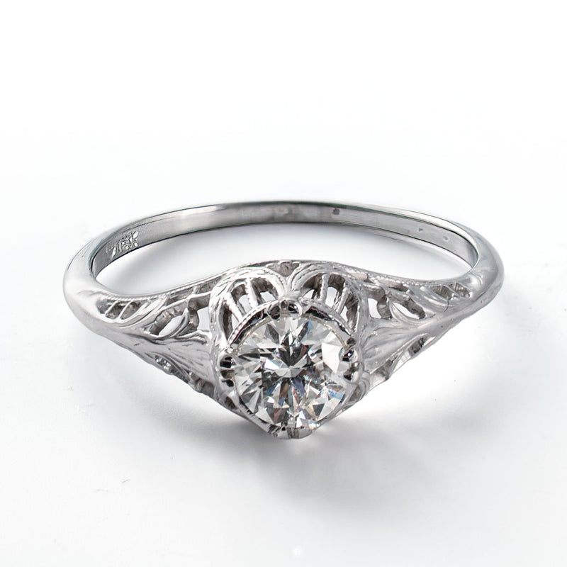 Elevated view of a vintage diamond solitaire ring with intricate openwork details