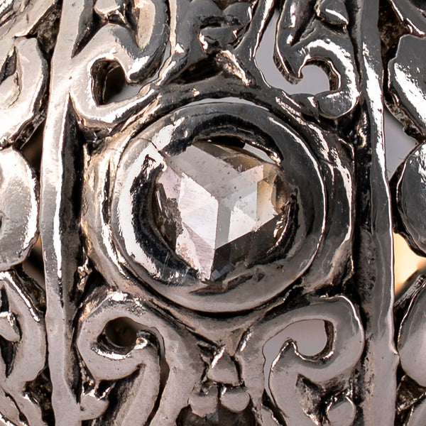 Extreme macro close-up of natural antique rose-cut center diamond displaying triangular facet pattern and bezel setting