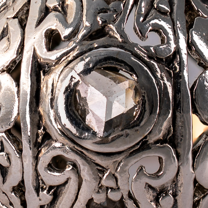 Extreme macro close-up of natural antique rose-cut center diamond displaying triangular facet pattern and bezel setting