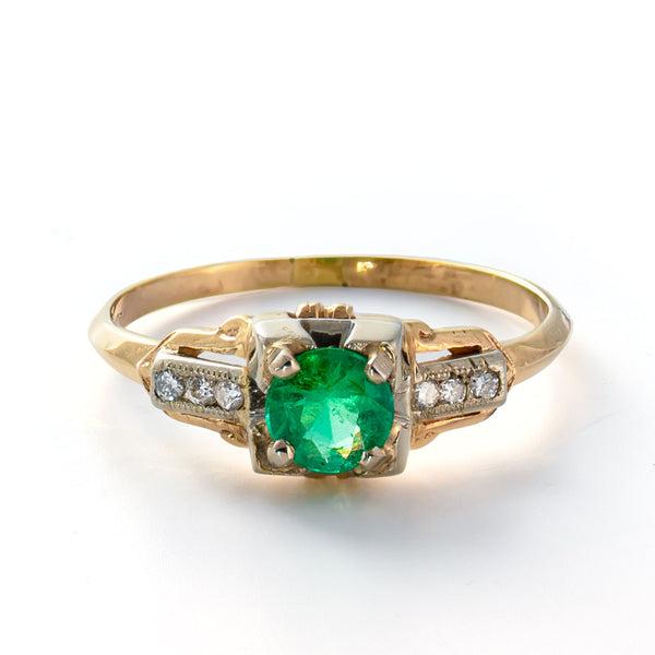 Elevated angle showing the emerald center stone, diamond-set shoulders, and transitional Art Deco