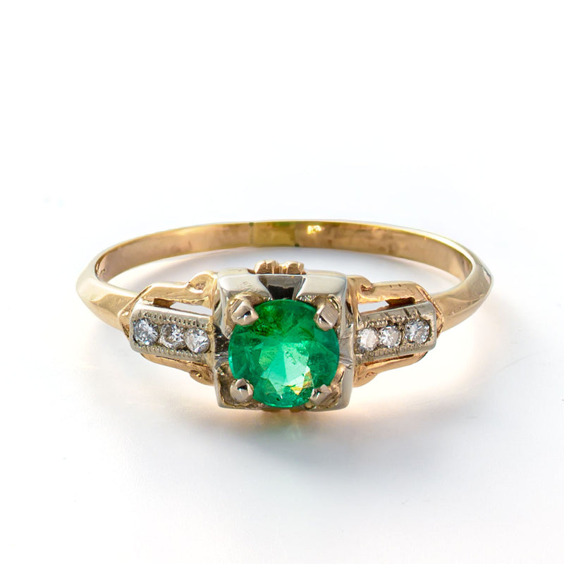 Elevated angle showing the emerald center stone, diamond-set shoulders, and transitional Art Deco