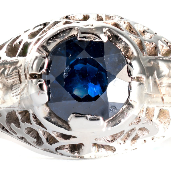 Macro view of a natural blue sapphire showing authentic period facet wear and surface patina.