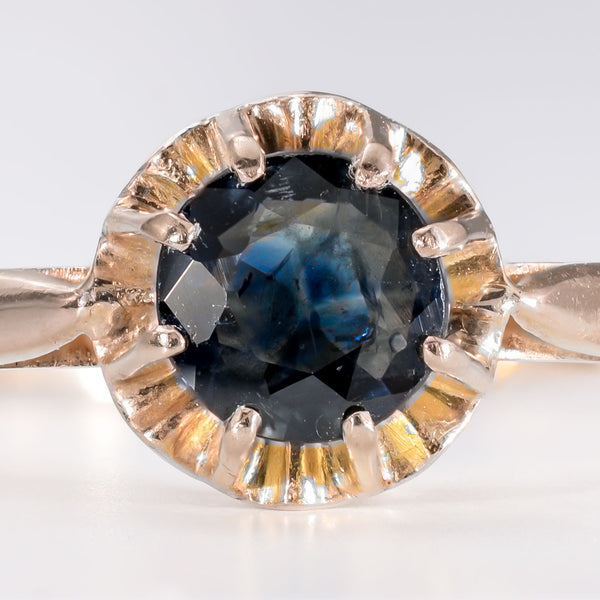 Close-up of a round mixed-cut natural blue sapphire showing characteristic internal silk and antique hand-cut facets.