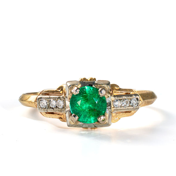 Front view of a vintage emerald and diamond ring displaying a vivid green emerald and geometric diamond accents.
