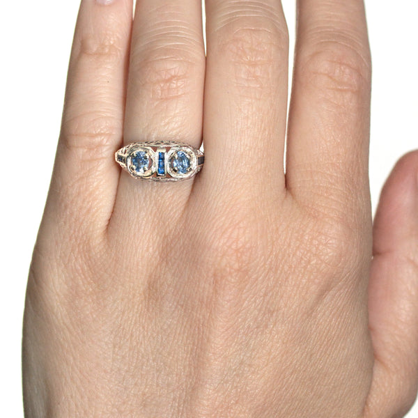 Close-up lifestyle image of an antique Edwardian sapphire ring worn on hand with delicate vintage styling.