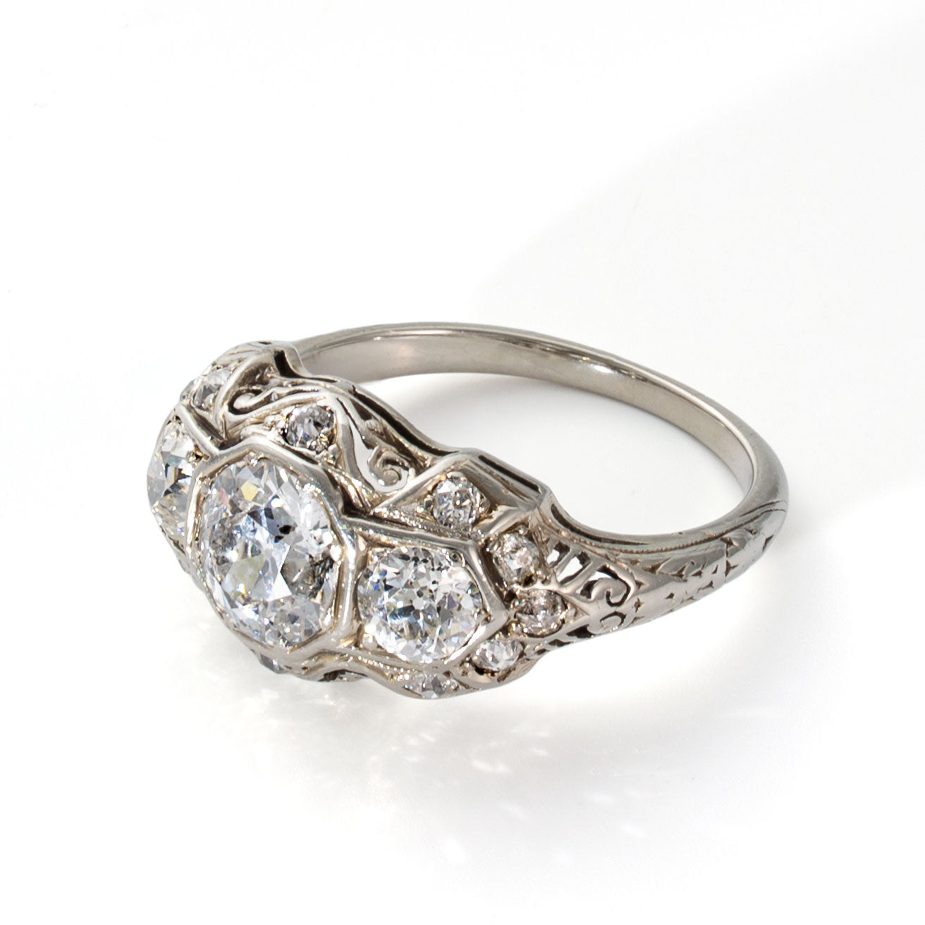 Right-side angle of an antique three stone diamond ring with layered illusion-style mounting