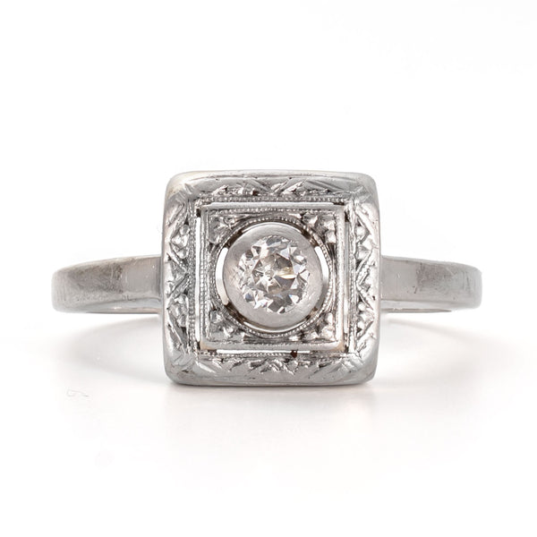 Straight on view of an Old European cut diamond framed within a recessed shield form bezel in 14K white gold