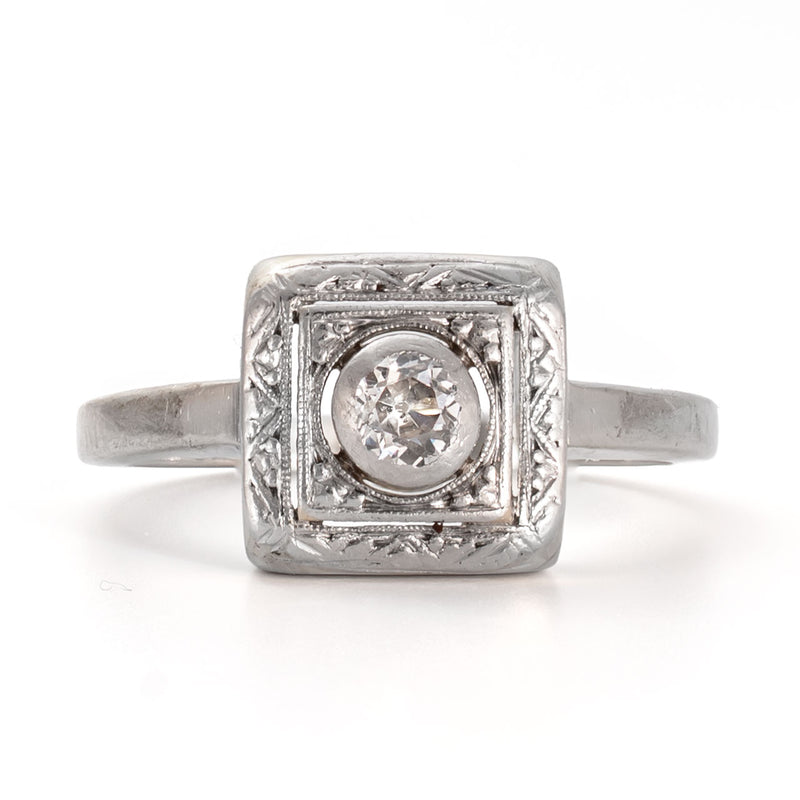 Straight on view of an Old European cut diamond framed within a recessed shield form bezel in 14K white gold