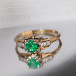 Vintage emerald and diamond ring featuring a richly colored natural emerald set in yellow and white gold with diamond accent shoulders.