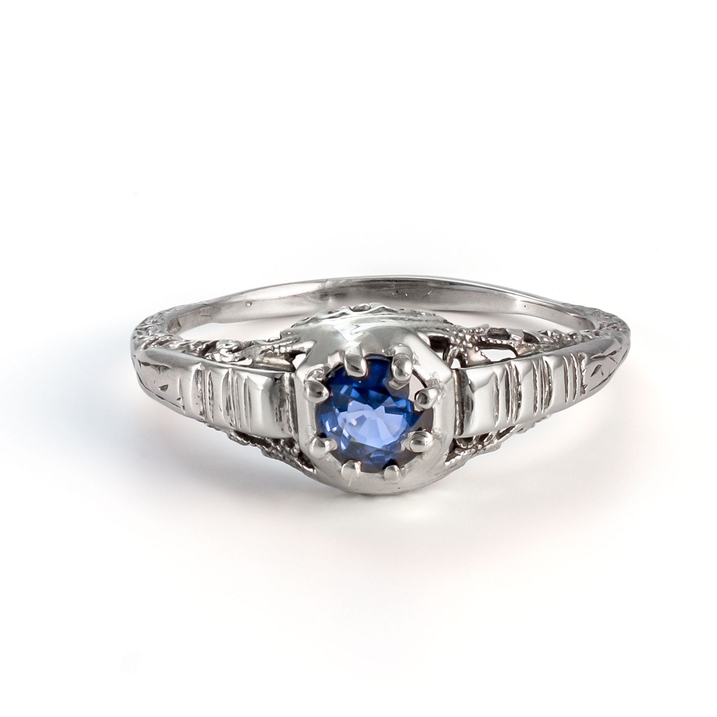 Elevated view of antique sapphire ring with intricate white gold filigree and natural blue sapphire