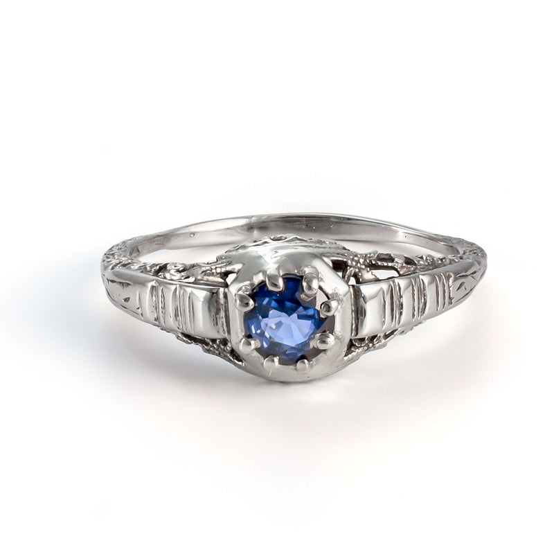 Elevated view of antique sapphire ring with intricate white gold filigree and natural blue sapphire