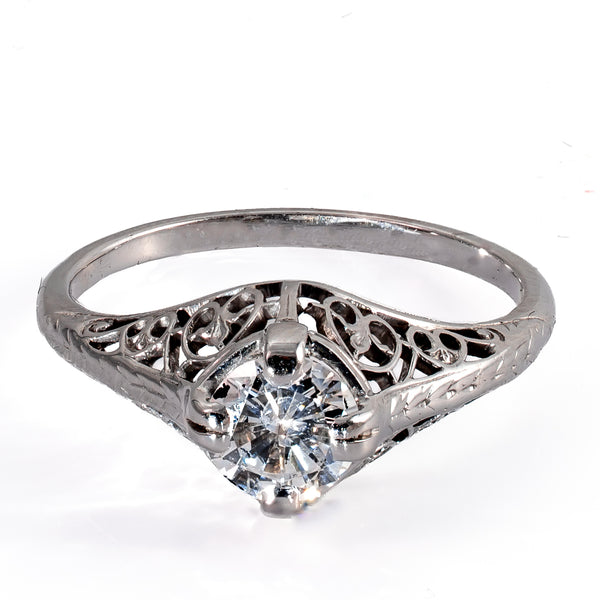 Elevated front view of a 1920s Art Deco diamond ring with pierced filigree mounting and engraved shoulders