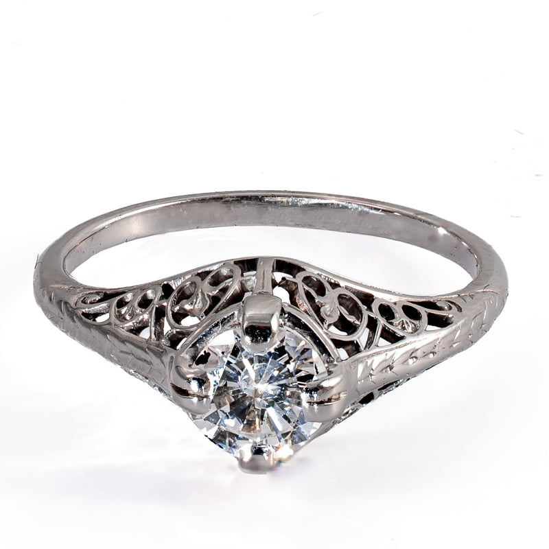 Elevated front view of a 1920s Art Deco diamond ring with pierced filigree mounting and engraved shoulders