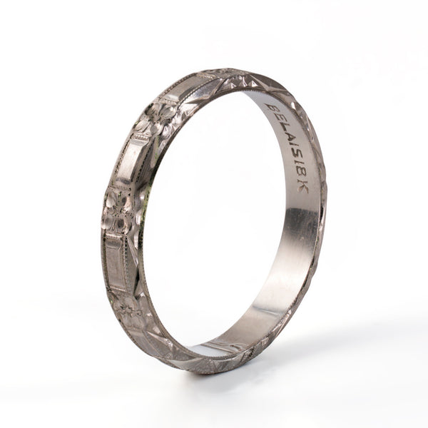 Three-quarter standing view of Belais 18K white gold band showing edge pattern and interior maker stamp.