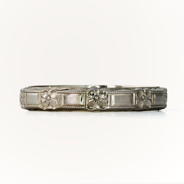 Front-facing view of antique Belais 18K white gold band highlighting repeating floral and rectangular panels.