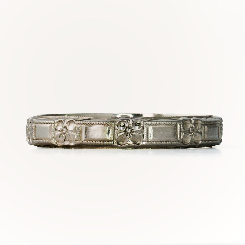 Front-facing view of antique Belais 18K white gold band highlighting repeating floral and rectangular panels.