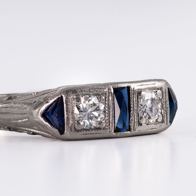 Macro detail photograph of the hand-cut Old European diamond, sharp triangular sapphire accent, and milgrain trim on a custom antique platinum ring.