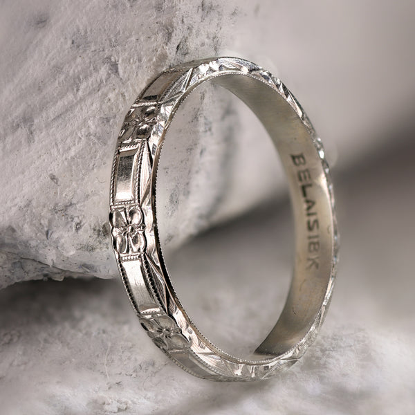 Angled profile of antique Belais 18K white gold band on stone displaying three-sided dimensional engraving.