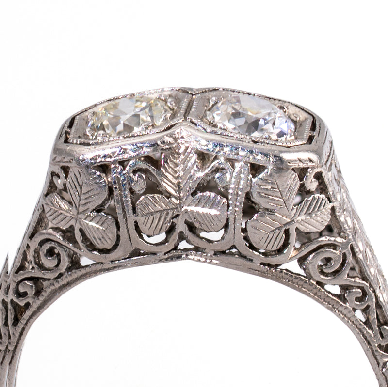 Extreme macro shot of the bespoke under-gallery on an Art Deco platinum ring, revealing hand-sawn shamrock petals and bench-tooled foliate filigree.
