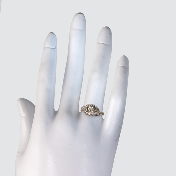 Edwardian Art Nouveau diamond bypass ring worn on the ring finger of a white mannequin hand.