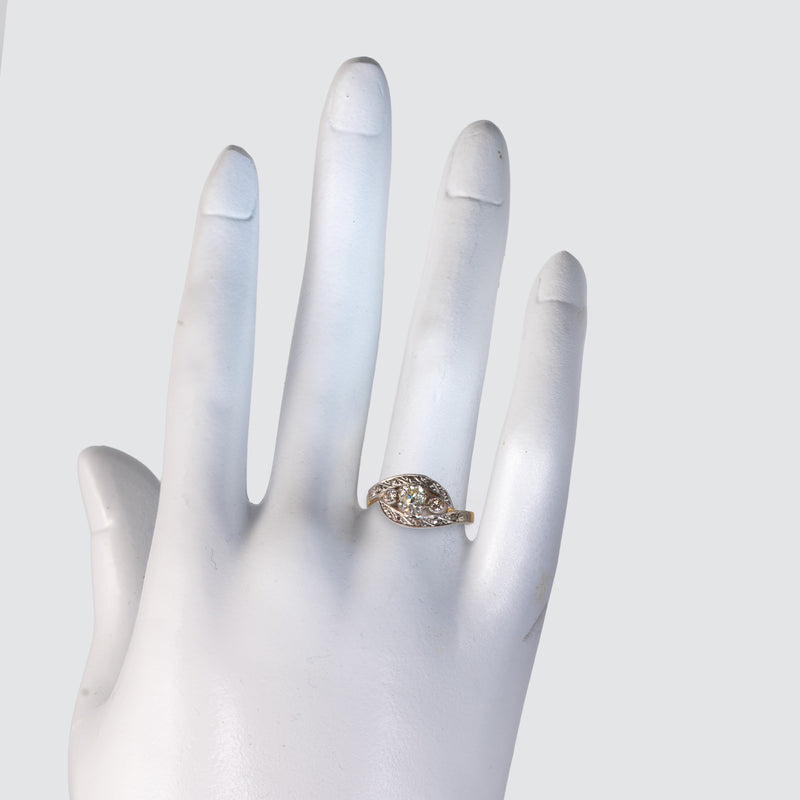 Edwardian Art Nouveau diamond bypass ring worn on the ring finger of a white mannequin hand.