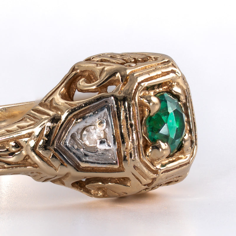 Extreme macro detail of the white metal shoulder accent holding a single cut diamond adjacent to the center emerald frame.
