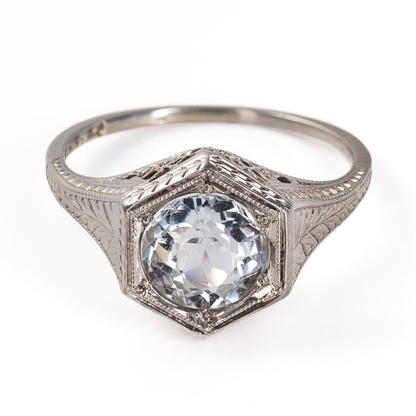 Elevated front view of an antique 1920s Belais Art Deco ring with a round faceted aquamarine set in a geometric white gold mounting