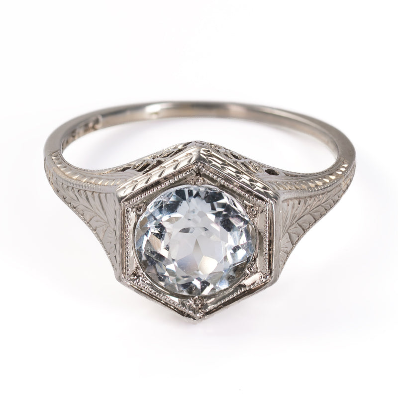 Elevated front view of an antique 1920s Belais Art Deco ring with a round faceted aquamarine set in a geometric white gold mounting