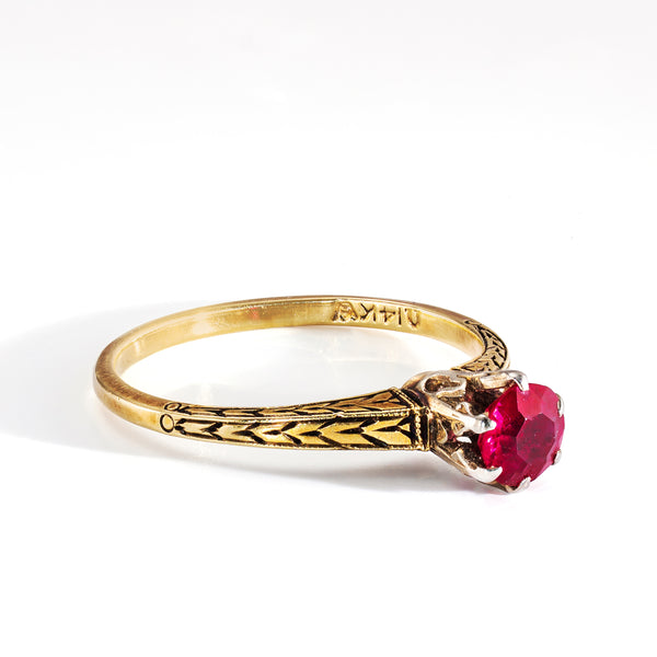 Gold ring with a red gemstone on a white background