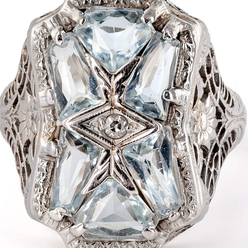 Macro detail of custom-cut aquamarine mosaic stones surrounding a bezel-set Old European cut center diamond.