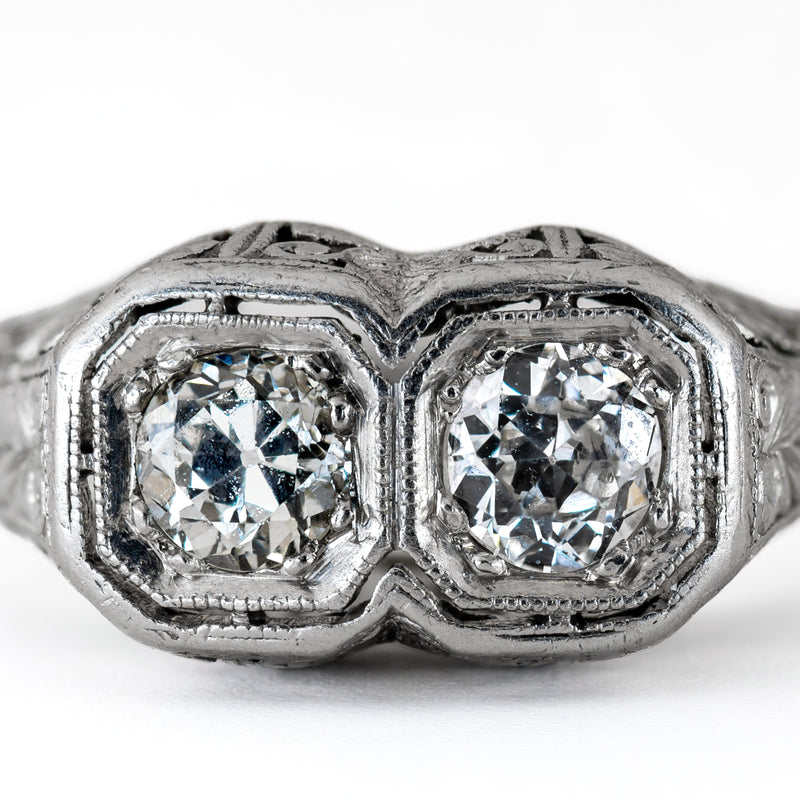 Macro shot of two matched Old European cut diamonds set in geometric, milgrained octagonal platinum bezels showing cut facets and open culets.